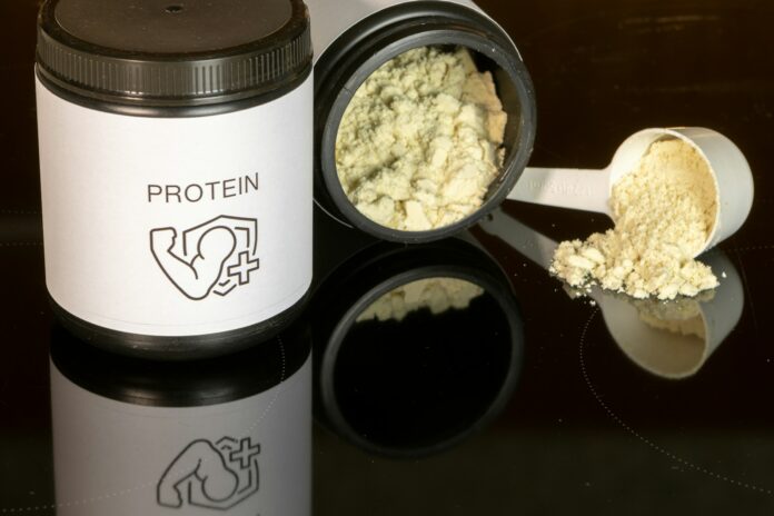Photo by Aleksander Saks a jar of protein powder next to a spoon
