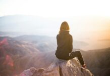 심리적 안정에 큰 역할을 하는 운동의 역할 person sitting on top of gray rock overlooking mountain during daytime