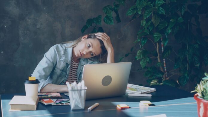Photo by Vitaly Gariev A woman appears stressed while working on laptop.