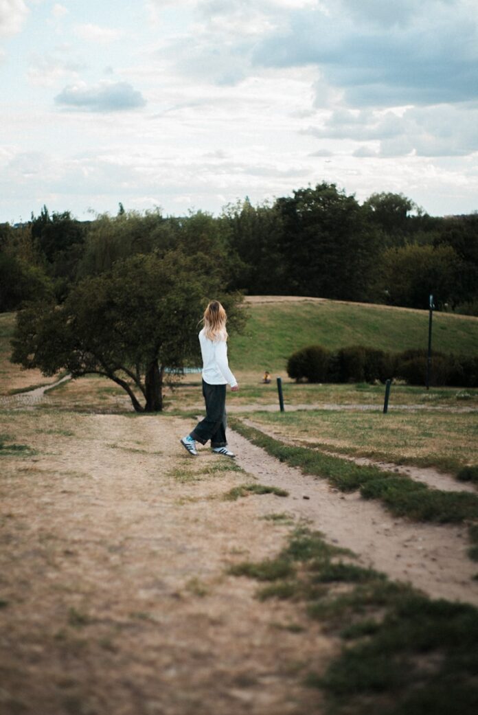 Photo by Mikita Tarasevich A person walks on a path in a grassy landscape.