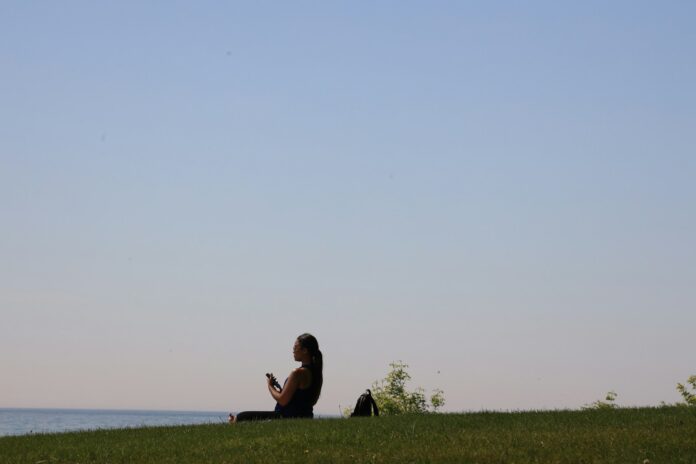 Photo by Richard Burlton a woman sitting on top of a lush green hillside