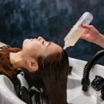 건강한 두피가 아름다운 머릿결을 만든다…일상 속 ‘헤어 루틴’ 실천법 주목 a woman getting her hair washed with a hair dryer