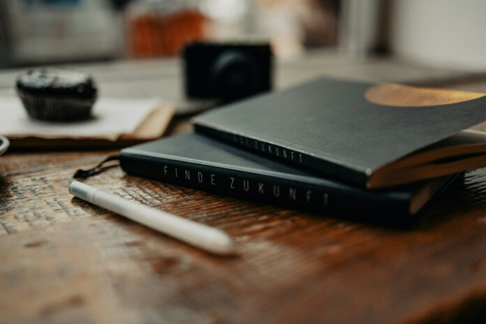 Photo by Finde Zukunft a couple of books sitting on top of a wooden table