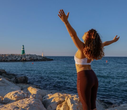 “마음도 체력처럼 단련…일상 속 정신건강 챙기는 5가지 루틴” woman in white sports bra and black bottoms standing on seashore