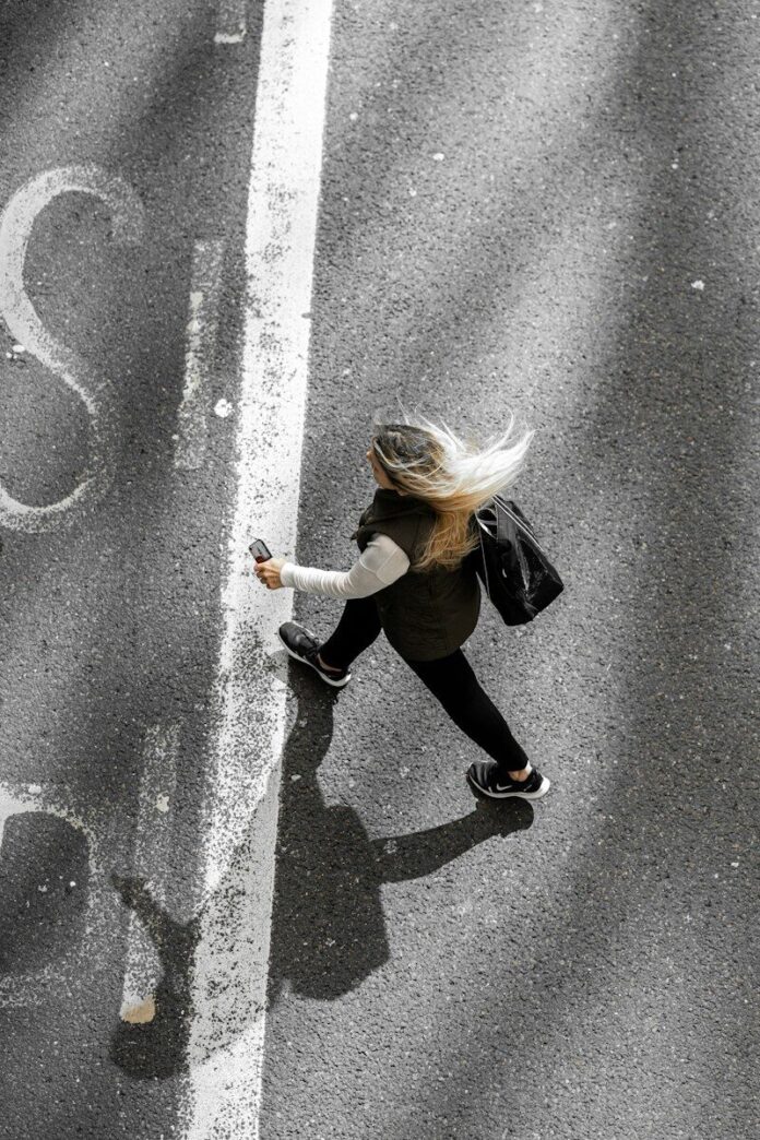 Photo by Krzysztof Hepner woman in black jacket and black pants walking on gray asphalt road during daytime